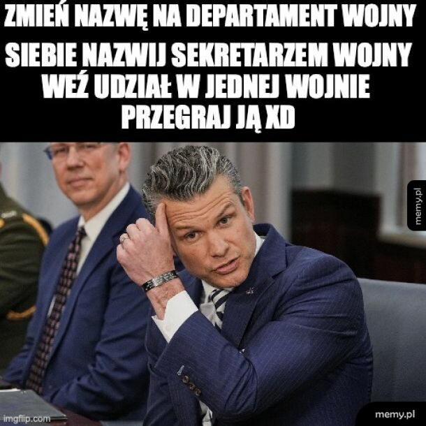 Mężczyzna w garniturze z ręką na głowie, siedzący przy stole.