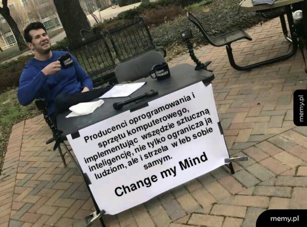 Mężczyzna siedzi przy stole z napisem i kubkiem.