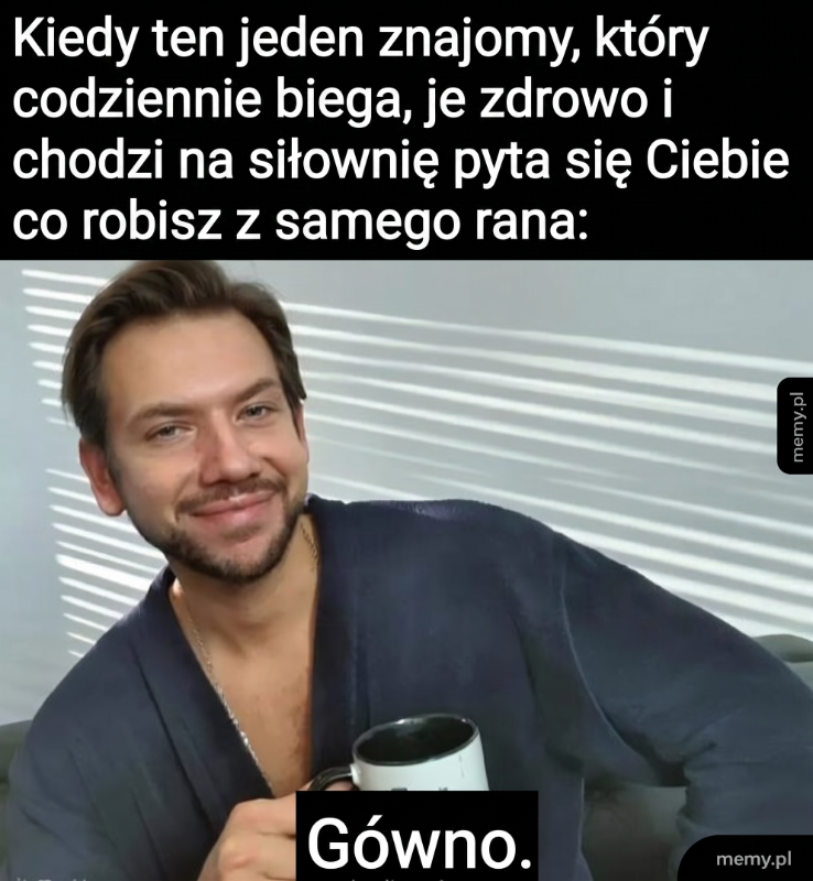 Mężczyzna trzyma kubek, uśmiecha się, w tle okno z zasłonami.