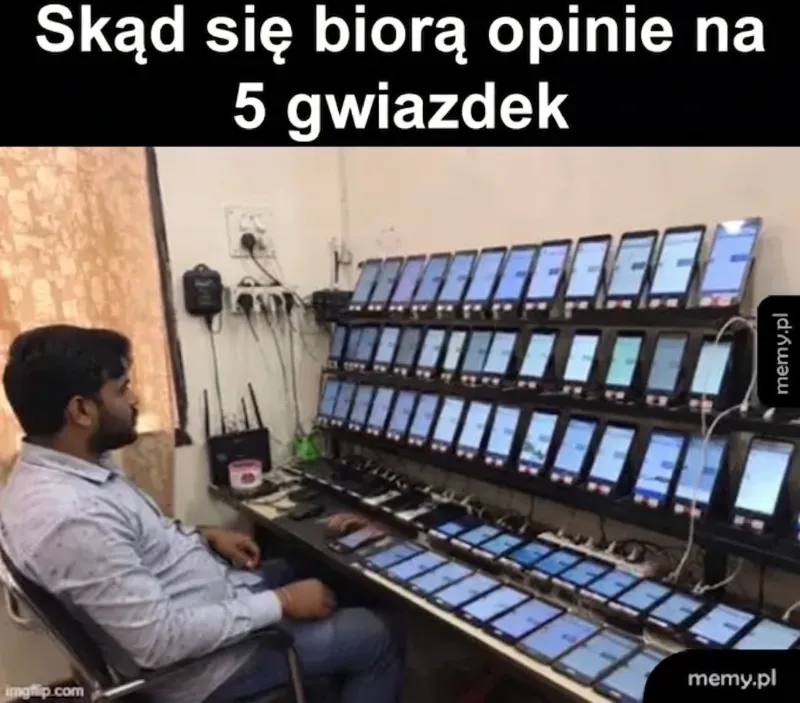 Mężczyzna siedzi przed wieloma telefonami komórkowymi ustawionymi w rzędach.