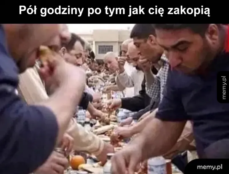 Grupa ludzi jedzących posiłek przy długim stole.