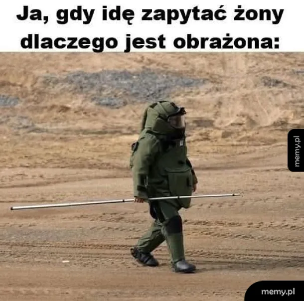 Osoba w kombinezonie ochronnym idzie przez teren.